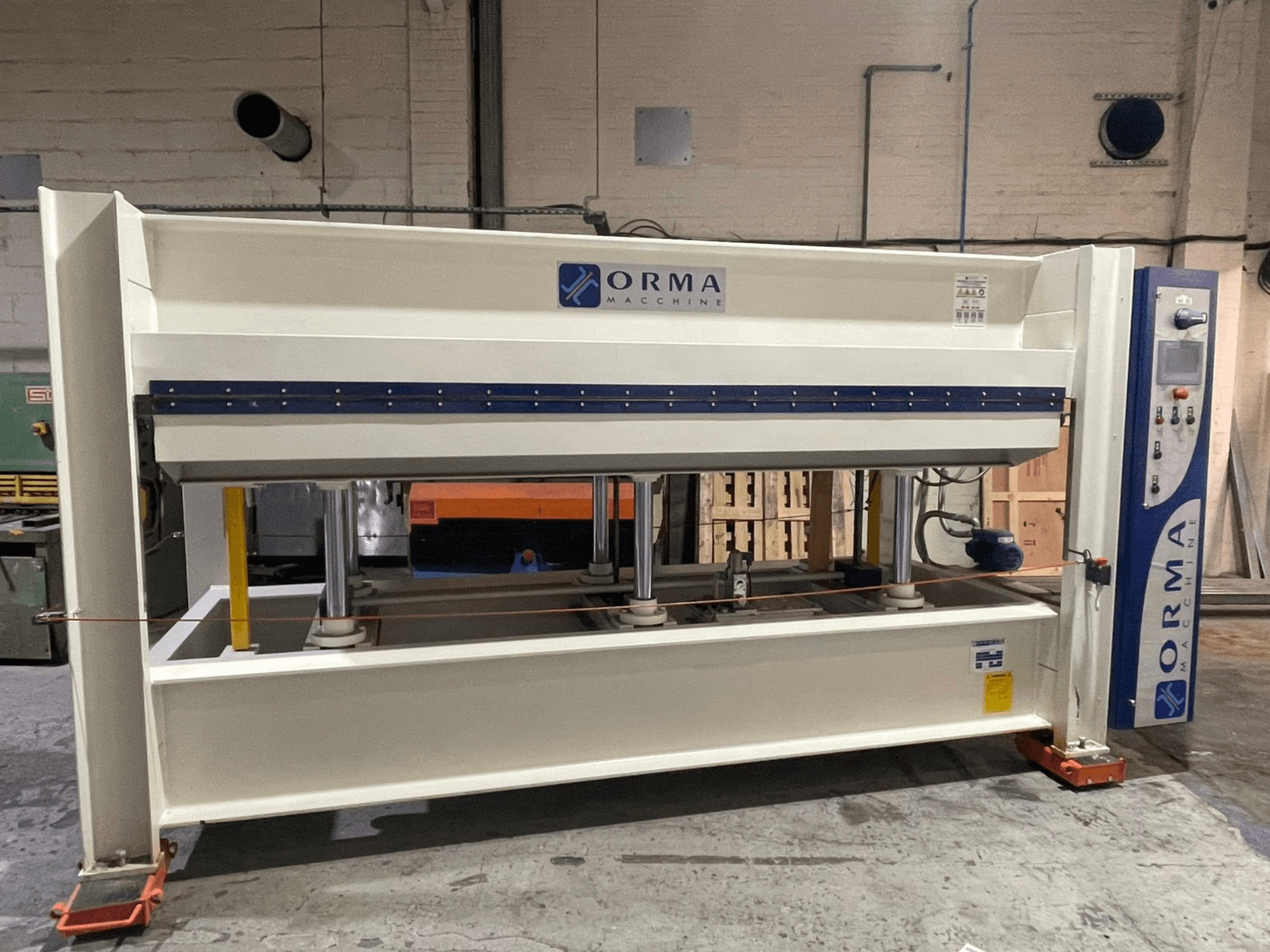 Orma Macchine hidrauliskā prese priekšpusē, ar četriem vertikāliem balstiem un vadības paneli labajā pusē.