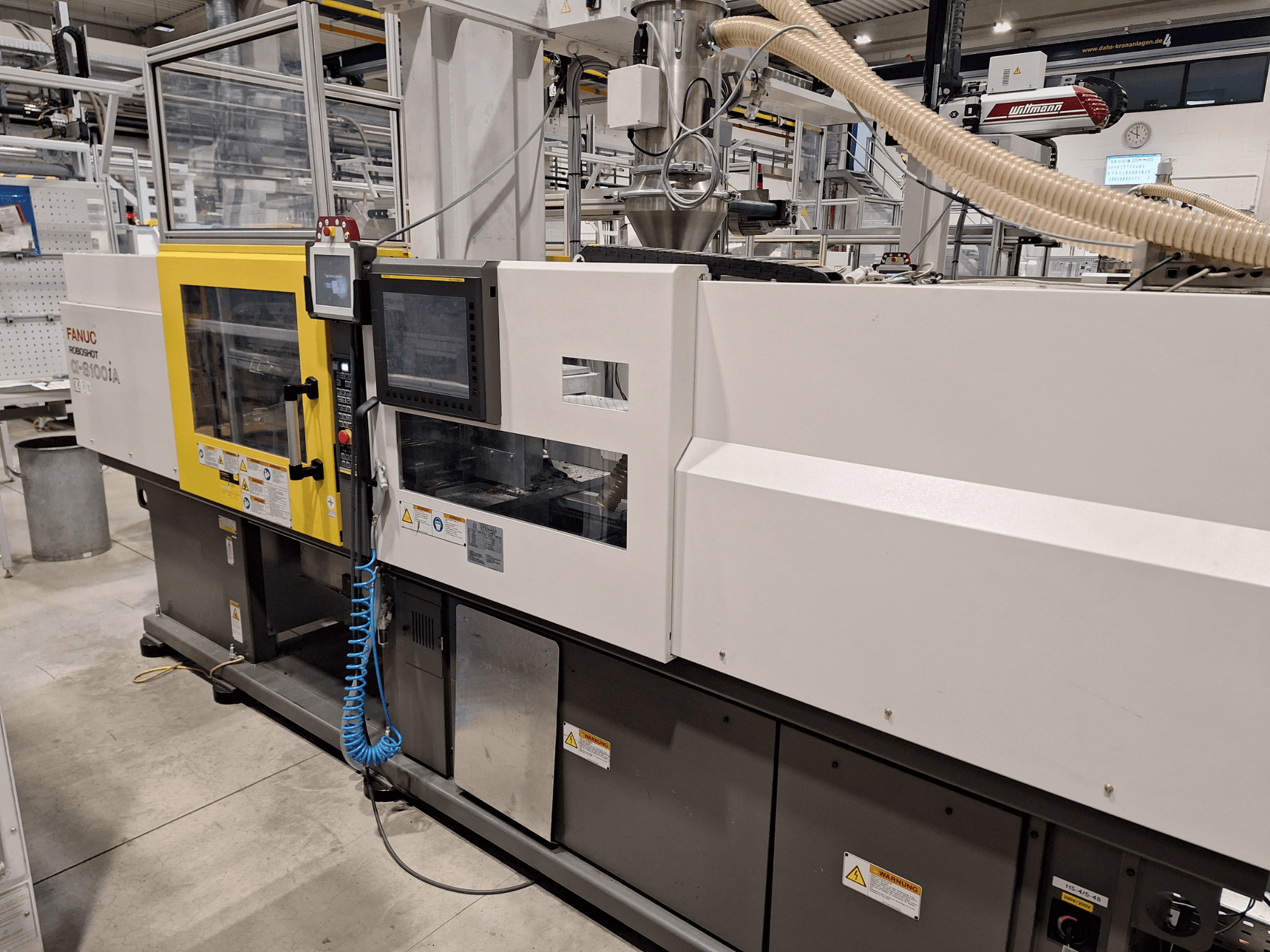 FANUC Roboshot α-S300iA injekcijas formēšanas iekārta, skats no priekšpuses, ar vadības paneli un redzamajiem rūpnieciskajiem komponentiem.